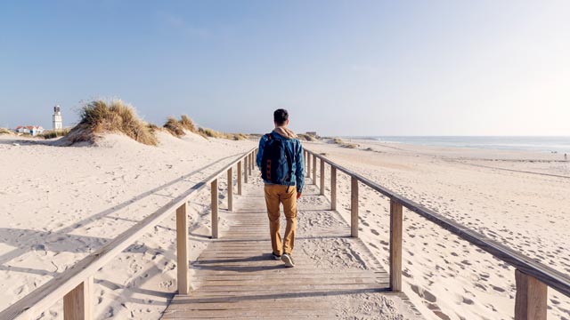 En kvinne med solhatt som står og ser utover landskapet på et tempel.